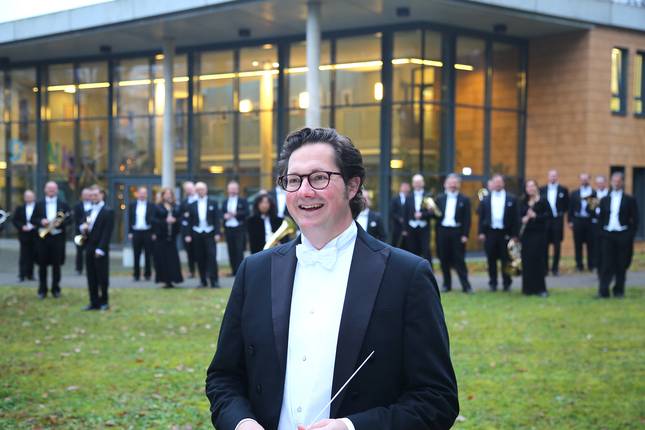Peter Sommerer, draußen vor der Sächsischen Bläserphilharmonie mit Orchester im Hintergrund